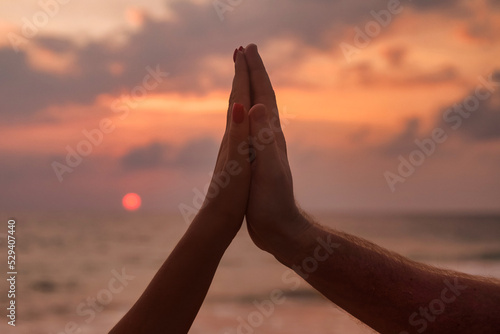 Silhouette sign hands of couple are lovely together at sunset of through. Woman and man hands in together sign shape with sunrise and sea (ocean) background. Togetherness and love concept. Copy space