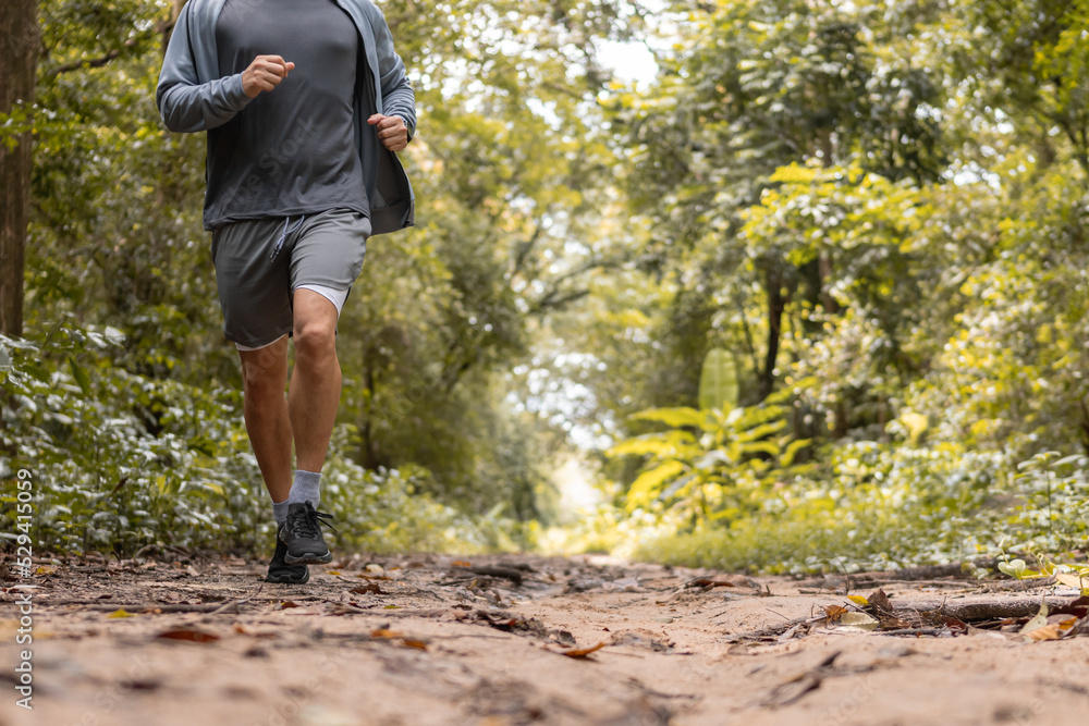 Close up man is jogging on path in forest outdoor. exercise, workout, running concept. Close up man is jogging on path in forest outdoor. exercise, workout, running concept.