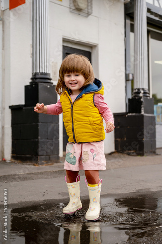 Corby, U.K., 08.09.2020. Toddler girl having fun in rain puddle, outdoor baby play activiy photo