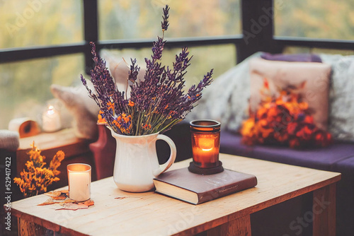 Autumn hygge home decor arrangement, concept of hygge and coziness, burning white fragrance candle photo