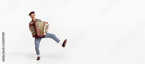 Portrait of young man playing accordion, posing isolated over white studio background. Cheerful boy. Flyer image