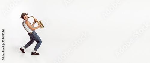 Obraz na plátně Portrait of stylish man in hat and suglasses playing saxophone , performing isolated over white background