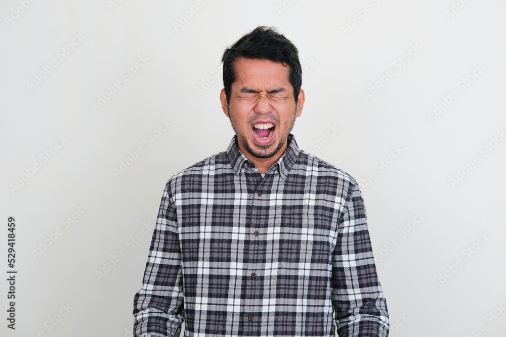Asian man screaming loud showing stressed expression Asian man screaming loud showing stressed expression