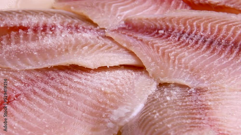 Pink tilapia fish, large pieces of fish fillet, close, lies on a plate. Pink tilapia fish, large pieces of fish fillet, close, lies on a plate.