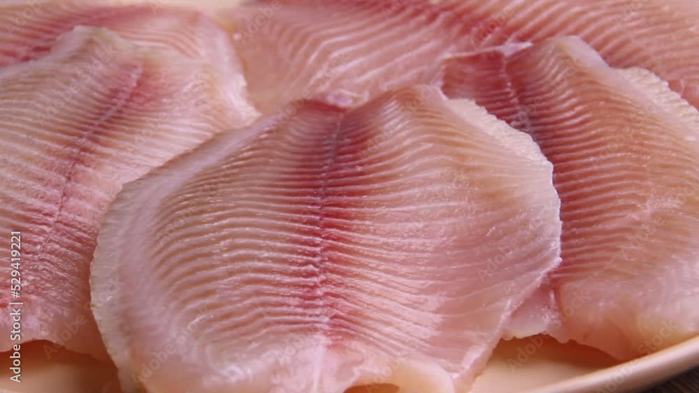 Pink tilapia fish, large pieces, close, lies on a plate Pink tilapia fish, large pieces, close, lies on a plate