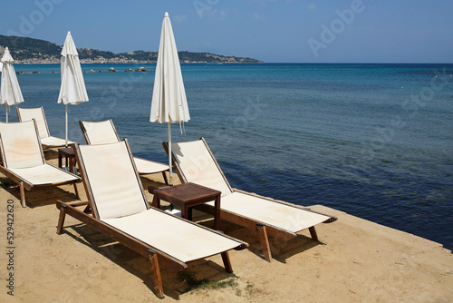 empty sunbeds and umbrellas by the sea on the greek island