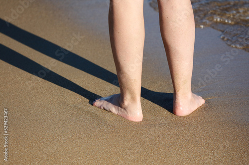 Legs of a woman on a sandy beach by the sea