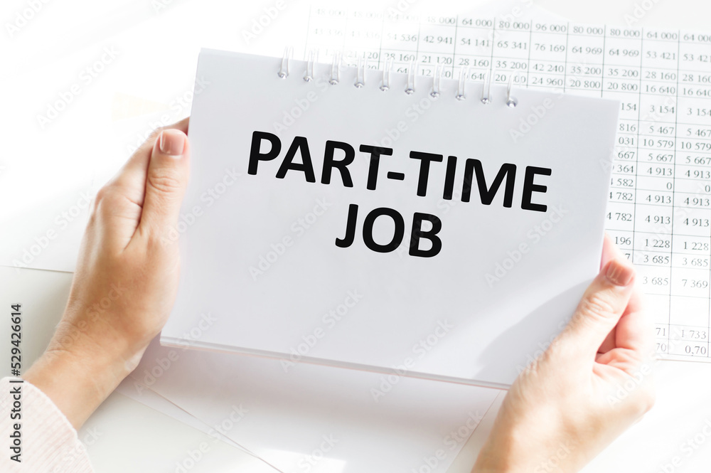 PART-TIME JOB text on a notebook in the hands of a businessman in the background of an office desk with documents