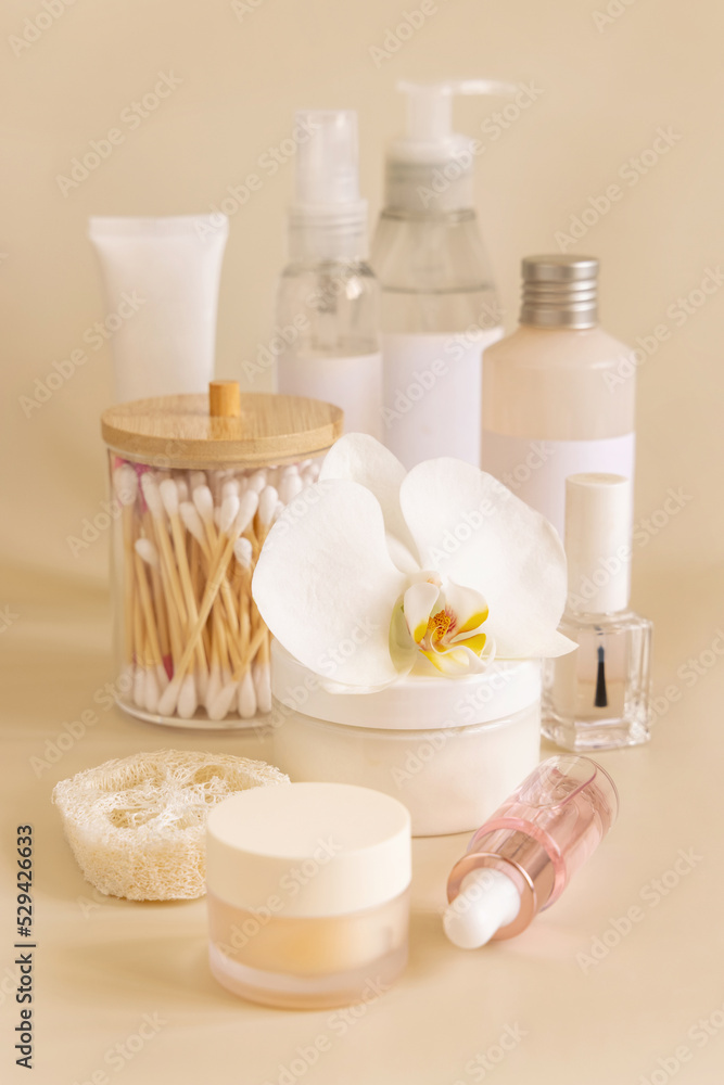 Natural cosmetic jars and skin care accesories with white orchid flower on beige close up
