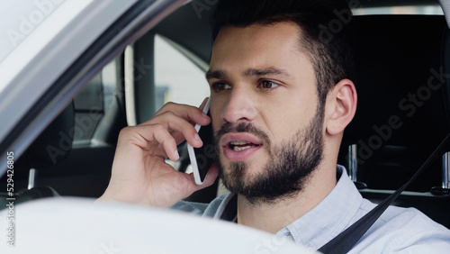 young man looking ahead and talking on cellphone while driving automobile.