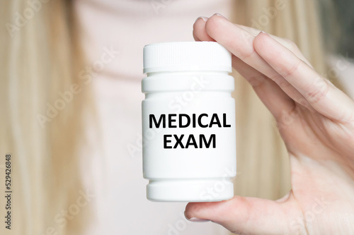 Medical concept. MEDICAL EXAM inscription on a white can on a label in the hands of a doctor, close-up