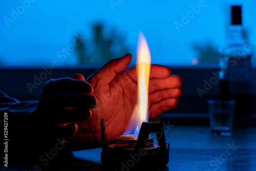 a man warmed his hands from an alcohol lamp in the absence of heating concept of the energy crisis in Europe caused by the rejection of fossil fuels. Blackout photo