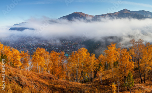 Autumn view, Altai nature. Fog above the mountain valley, the village below.