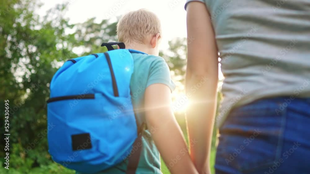 mother and son go to school. happy family education concept. schoolgirl with mom and son go hand in hand to school along the path in the park. little son. time to study briefcase mother and son go to school. happy family education concept. schoolgirl with mom and son go hand in hand to school along the path in the park. little son. time to study briefcase