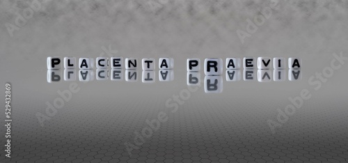 placenta praevia word or concept represented by black and white letter cubes on a grey horizon background stretching to infinity photo