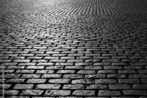 Old cobblestones on Market place “Grote Markt“ in Antwerp Belgium. Shiny historic basalt ashlars and blocks reflecting sunshine. Pavement background, black and white greyscale with high contrast.