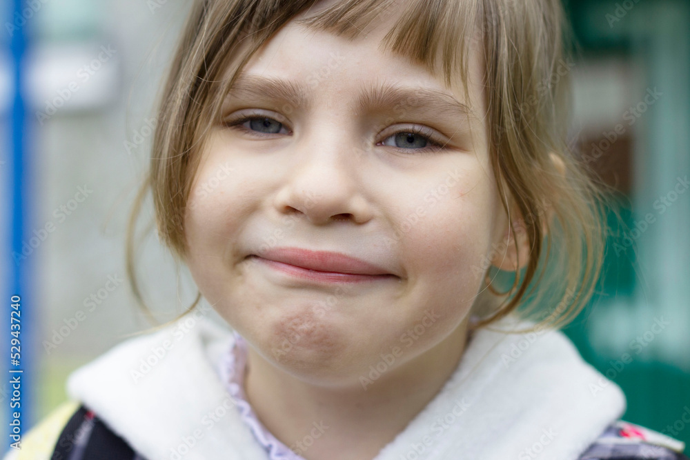 Portrait of a little upset girl who is forced to do what she does not want. She looks like she's tired