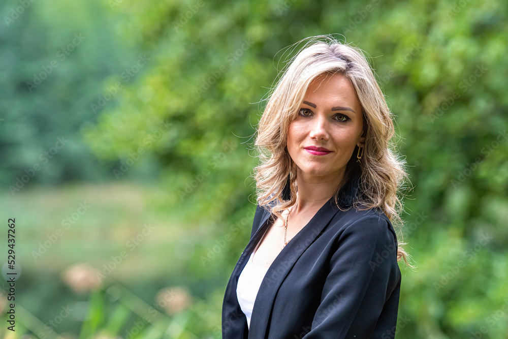 portrait of a blond woman in summer in front of green background