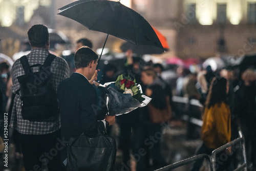 Fotomurale People mourn and bring flowers under the rain outside Buckingham Palace after Qu