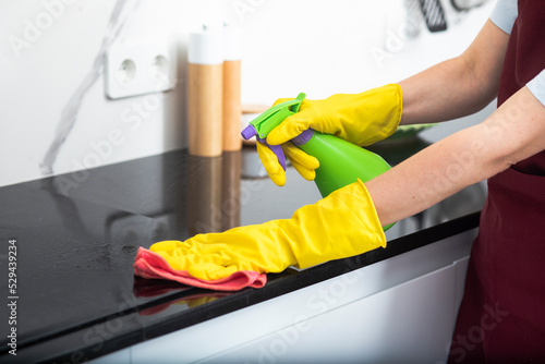 Close up shot of female hands holding bottle spray and rag for cleaning the stove 