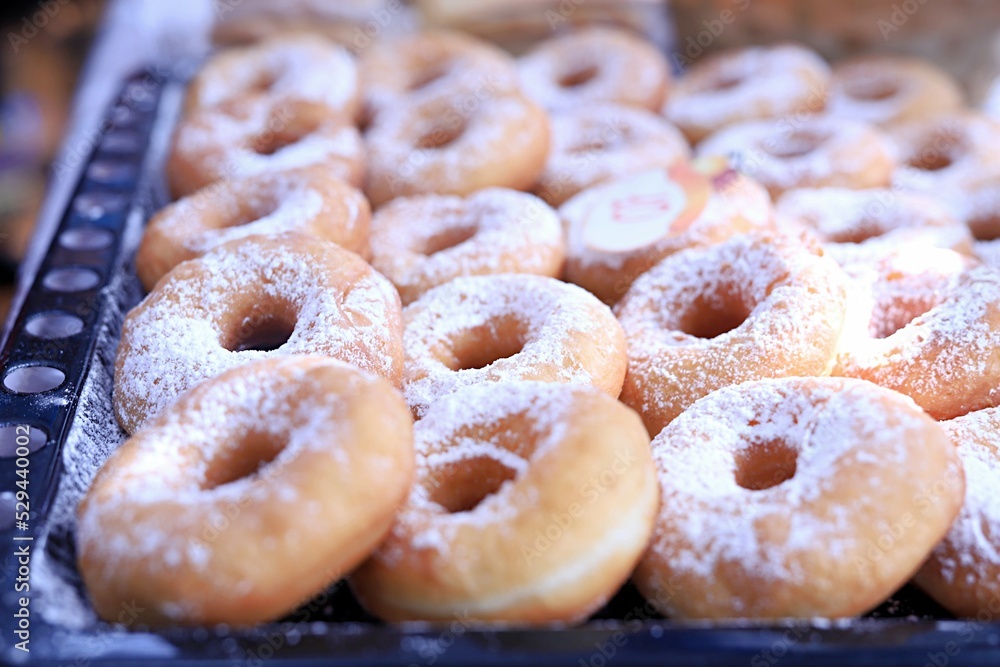baking sheet with donuts sprinkled with powdered sugar. sweet dessert. junk food concept