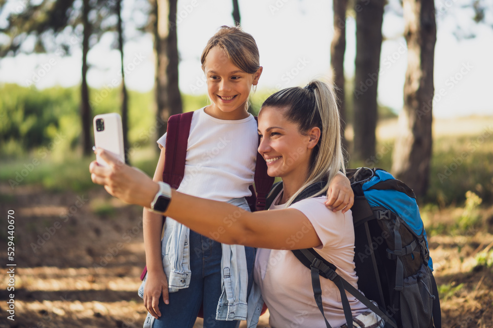 Mother and daughter are  taking selfie while enjoy hiking.