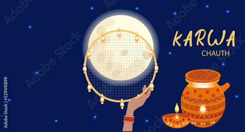 Happy Karwa Chauth festival card with a hand holding a traditionally ornate sieve in the night sky with the moon. photo