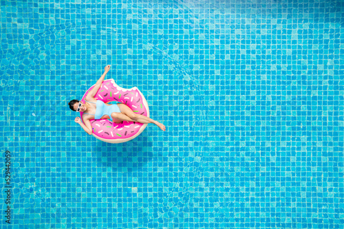 Top view of young asian woman in swimsuit on the pink donut lilo in the swimming pool.