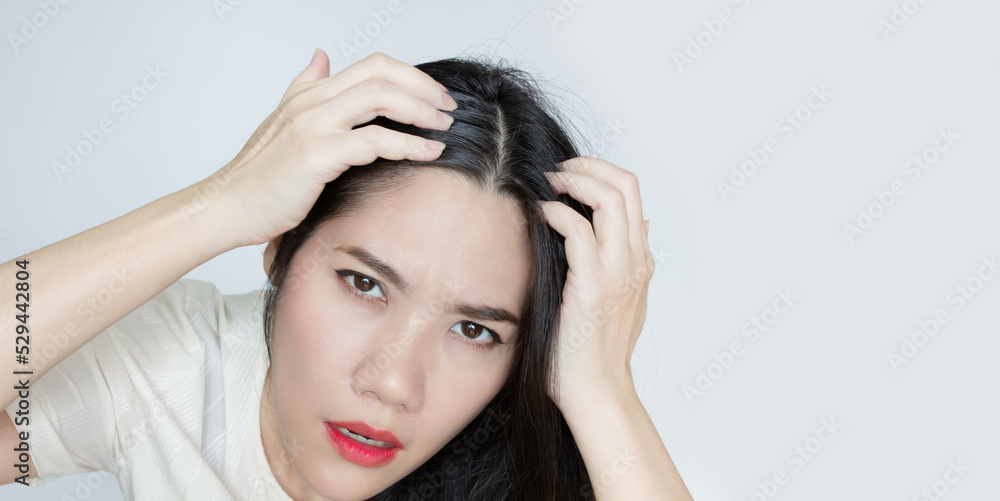 Asian Beautiful woman use hand touch her head and looking to check grey hair with worry face. Asian Beautiful woman use hand touch her head and looking to check grey hair with worry face.