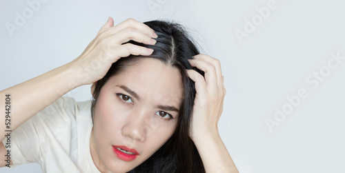 Asian Beautiful woman use hand touch her head and looking to check grey hair with worry face.