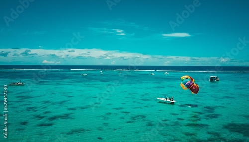 Photo Colorful parachute connected to a motorboat riding on the beautiful sea on a bright blue day