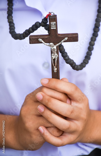 Brown wooden cross holding in hands who dresses in a white uniform