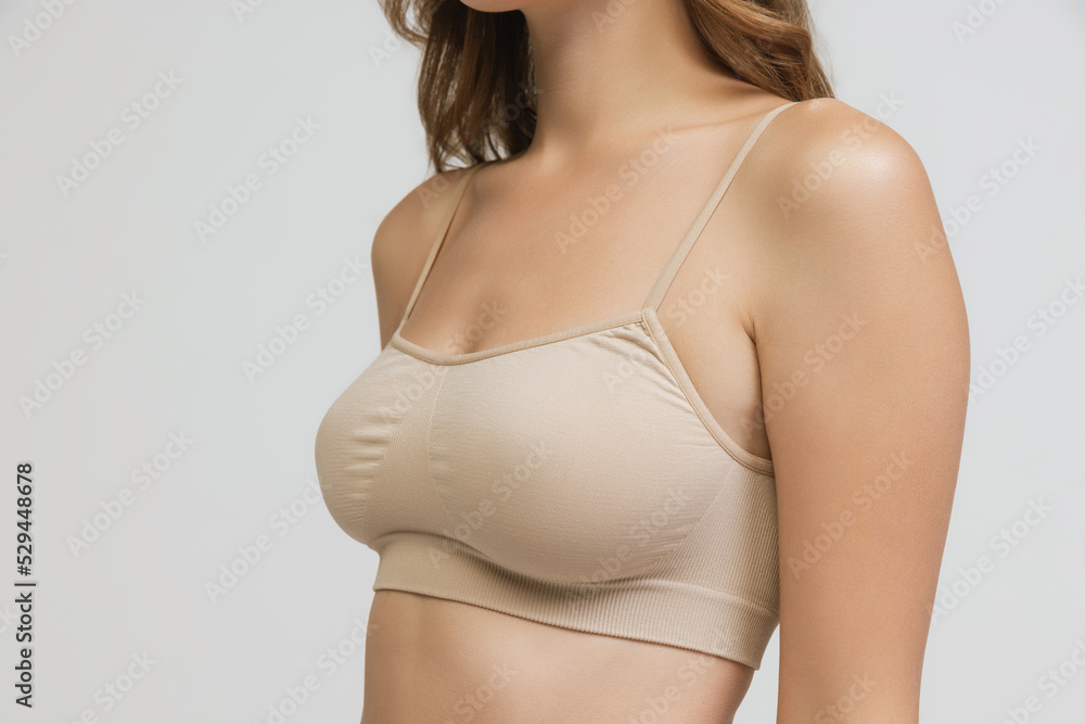 Cropped image of slender female body, breast and shoulders isolated over grey studio background. Cancer prevention. Concept of beauty, fashion, body care
