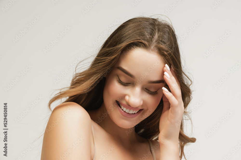 Closeup portrait of young cheerful beautiful girl with curly long hair smiling and looking at camera with happy and relaxed face expression Closeup portrait of young cheerful beautiful girl with curly long hair smiling and looking at camera with happy and relaxed face expression