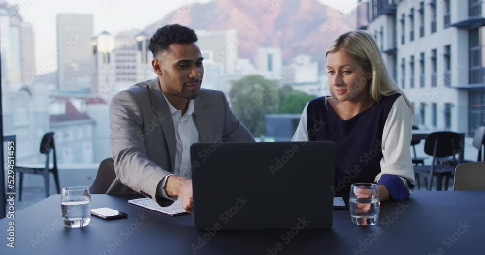 Video of two diverse male and female colleagues discussing and using laptop in office Video of two diverse male and female colleagues discussing and using laptop in office