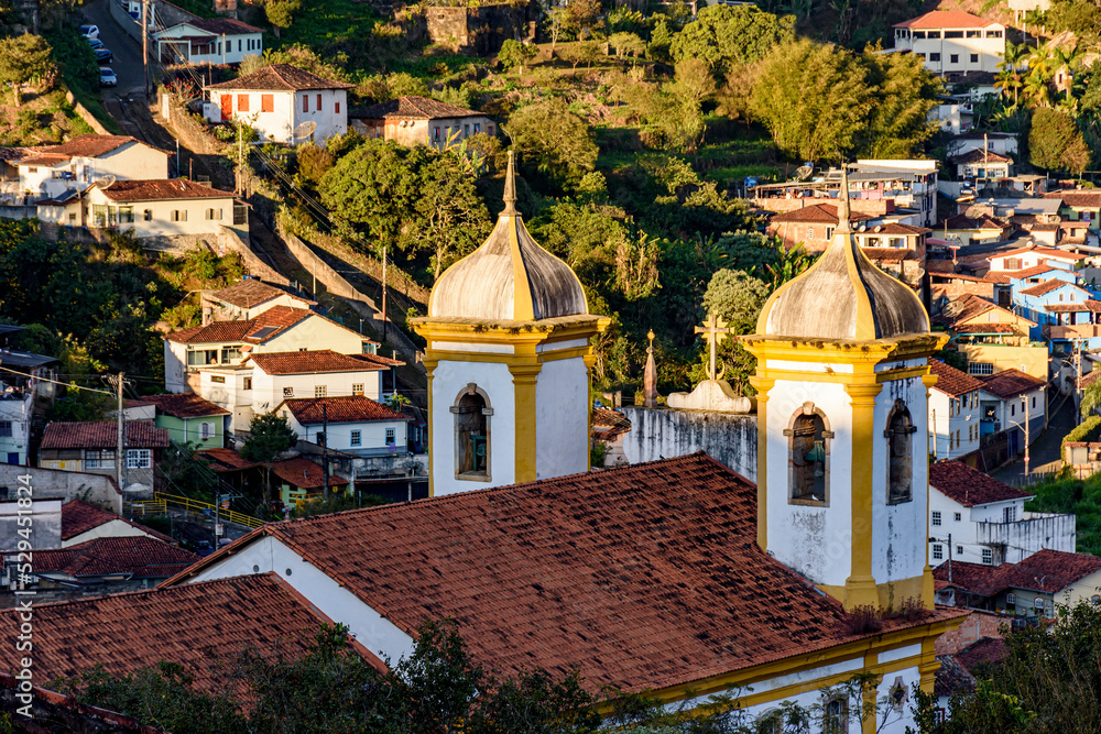 Towers and bells of an old baroque church with the houses of Ouro Preto city in the background