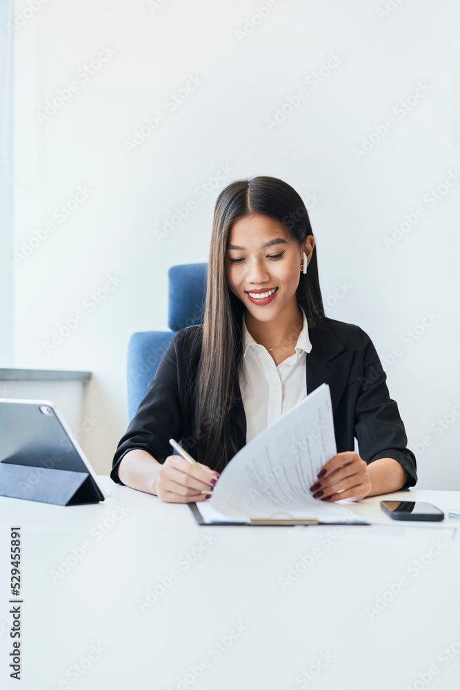 Portrait of young Asian woman signing documents at office Portrait of young Asian woman signing documents at office