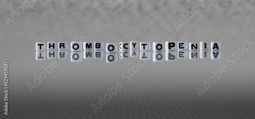 thrombocytopenia word or concept represented by black and white letter cubes on a grey horizon background stretching to infinity
