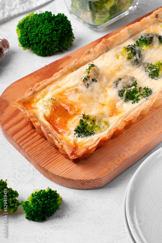 Broccoli tart on shortbread dough of rectangular shape on wooden board. Savory pie with vegetable