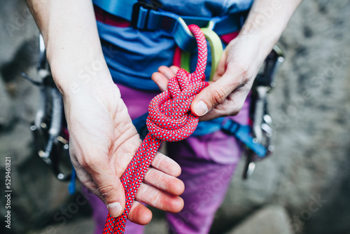 Female rock climber prepares equipment for climbing, a woman holds a rope in her hands, a climber ties a knot