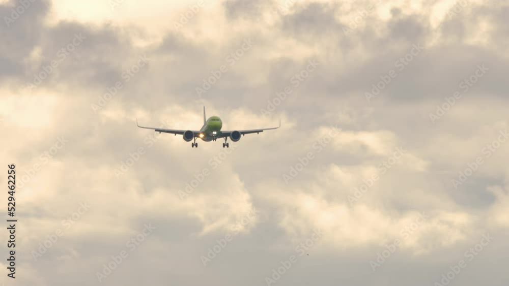 Aircraft landing approach, front view, slow motion. Airplane on the background of a beautiful cloudy sky at sunrise or sunset. Tourism and aviation concept Aircraft landing approach, front view, slow motion. Airplane on the background of a beautiful cloudy sky at sunrise or sunset. Tourism and aviation concept
