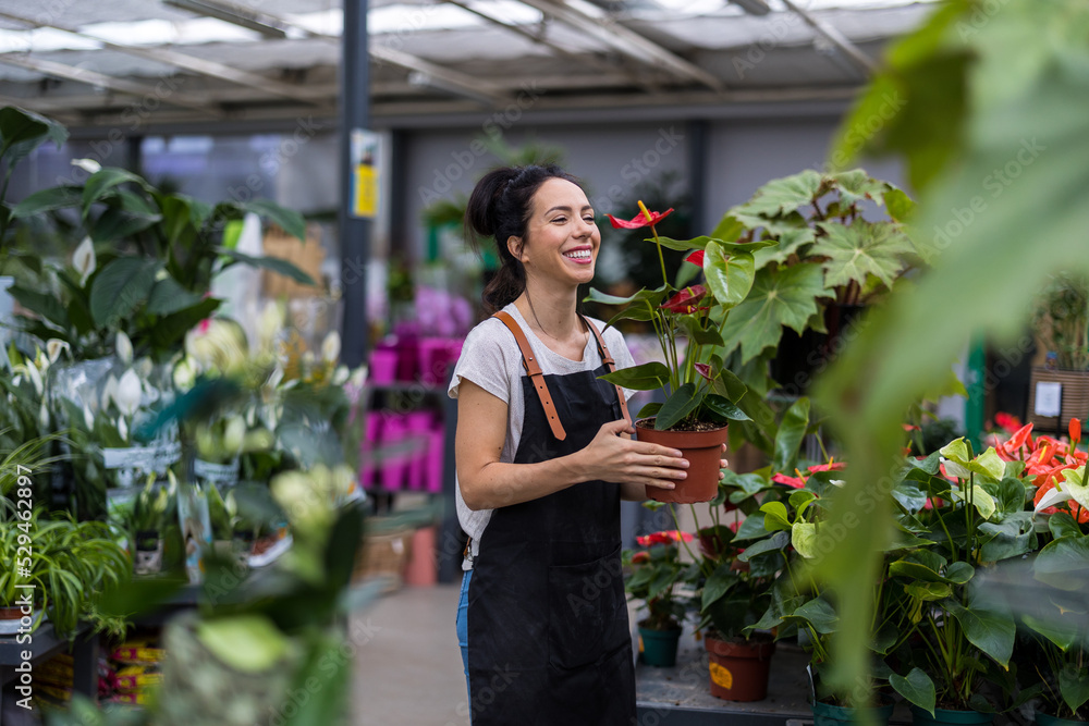 Fototapeta premium Shot of a young woman working with plants in a garden centre