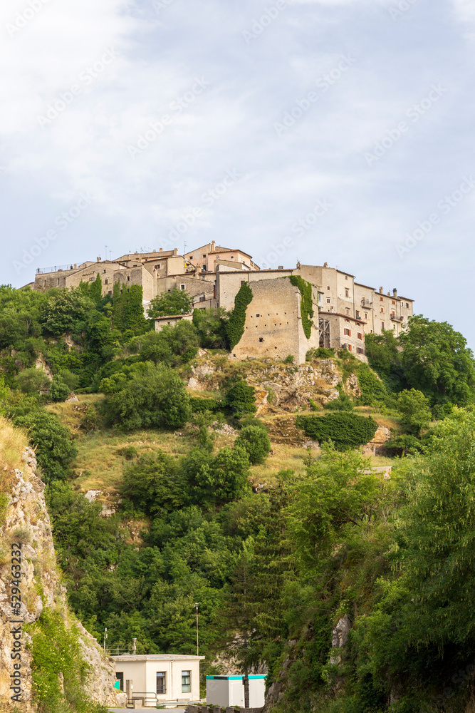 Village on top of a mountain in the middle of the green. Ancient stone houses, Abruzzo, Italy. Vertical view.