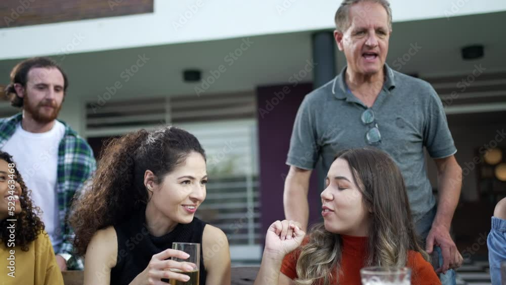 Friends and family gathered together for barbecue in home backyard party. People celebrating life toasting with drinks Friends and family gathered together for barbecue in home backyard party. People celebrating life toasting with drinks
