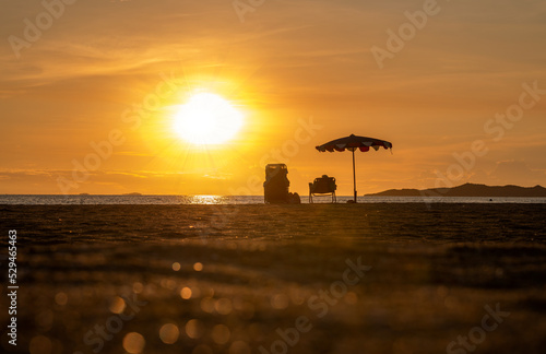 Silhouette beach chair with umbrella on beach with sun sky background. 