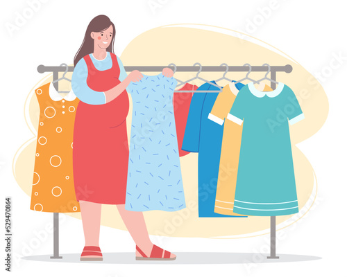 Pregnant  woman chooses  dress in maternity clothing store. She's standing by the clothes rack