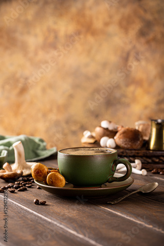 Trendy superfood mushroom coffee in green cup on wooden background. Healthy concept with copy space, selective focus.
