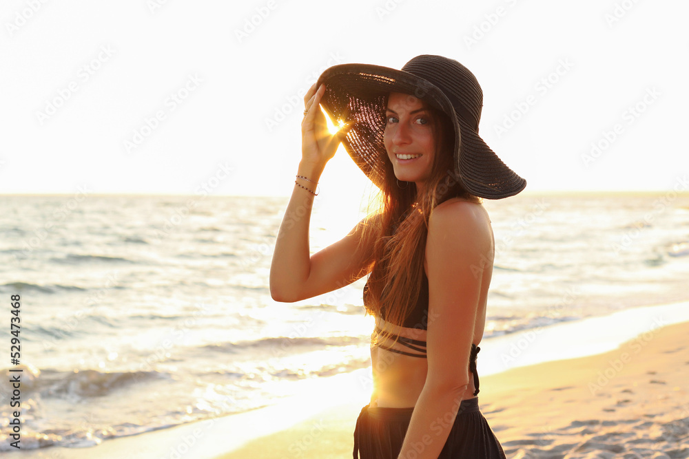 Young girl on the beach in a swimsuit, pareo, big straw hat Young girl on the beach in a swimsuit, pareo, big straw hat