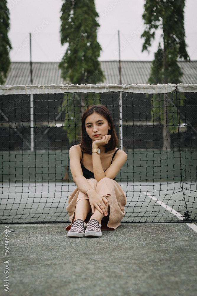Beautiful female model, wearing a black tanktop, posing and stylish in the middle of a tennis court in the afternoon. Beautiful female model, wearing a black tanktop, posing and stylish in the middle of a tennis court in the afternoon.