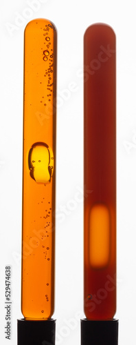 Yellow viscous liquid sunflower lecithin with bubbles in a transparent test tube on a white background